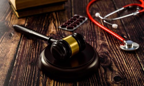Medical malpractice and errors makes doctors and patients go to court, gavel on legal books.
